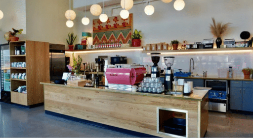 The inside of Broadcast Coffee café in Boise, Idaho. A bright and airy space with wood accents, coffee merchandise for sale, and a pink espresso machine.